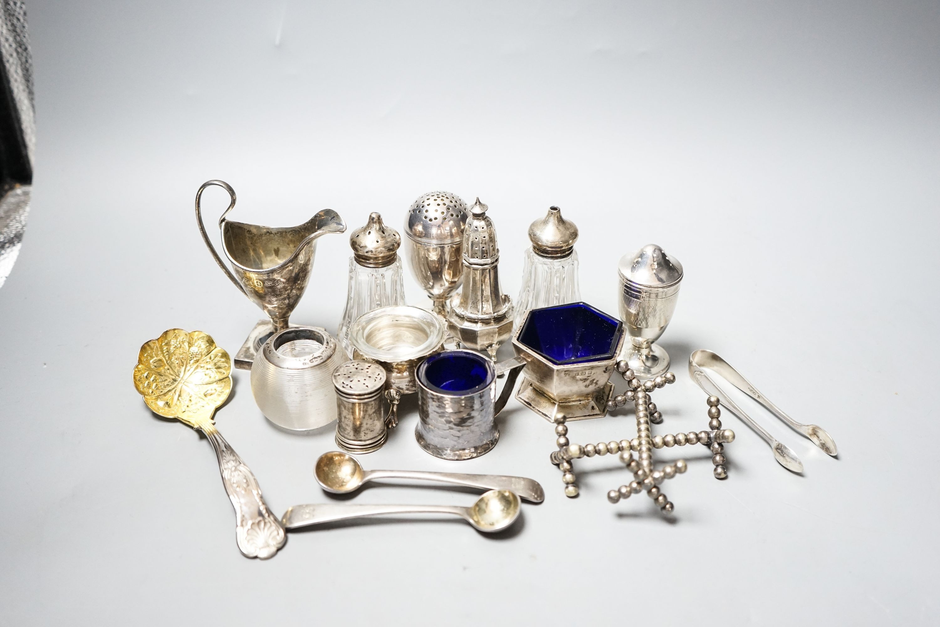 A group of small silver including condiments, match strike, cream jug, plated knife rests etc.